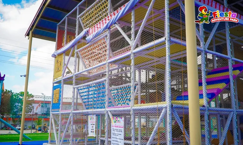 A steel climbing structure with colourful nets and platforms