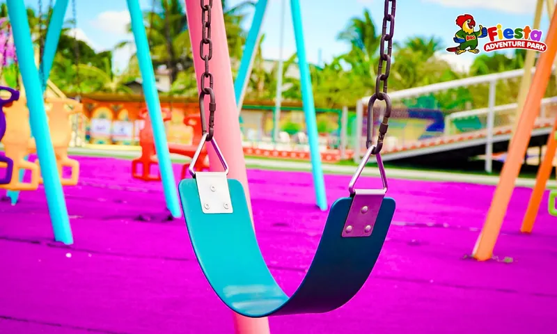 Tall pink and blue giant swings over a purple play surface with palm trees behind
