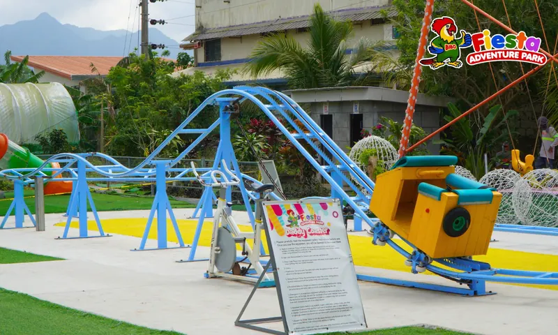 A small blue roller coaster track with a yellow car on a green lawn