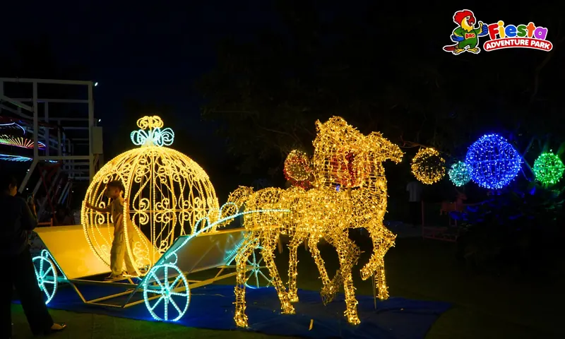 A glowing golden carriage pulled by illuminated horses in a night-time light display