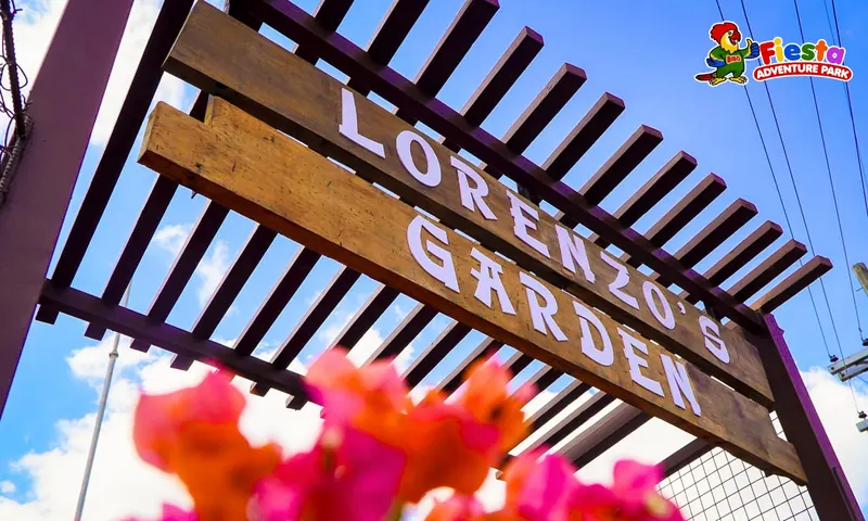 A wooden Lorenzo's Garden sign framed by pink flowers