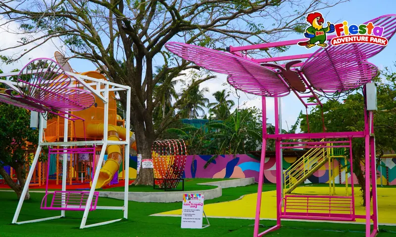 A pink swing frame on a purple play surface beside a lawn