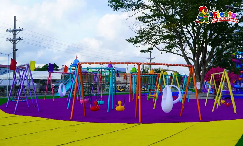 Colourful swings on a purple play surface framed by a leafy tree