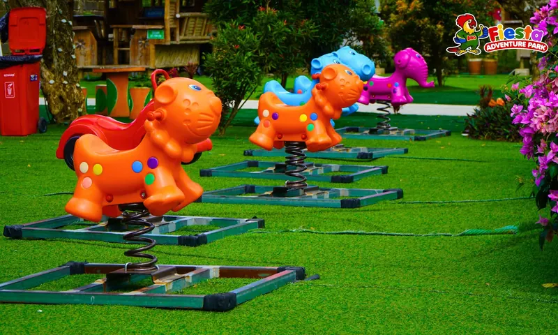 Orange and pink ride-on animal rides parked on the grass
