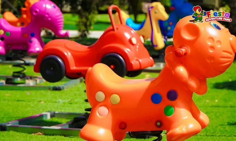 Orange rocking animal rides with white spots on a lawn