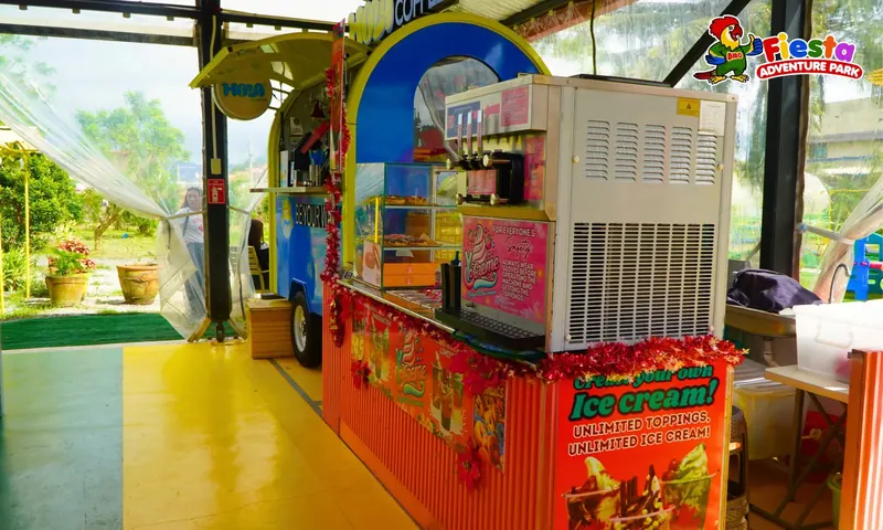 A colourful snack and ice cream cart in a covered food area