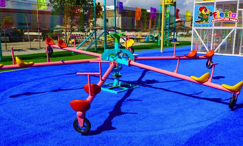 A pink spinning ride with bucket seats on a blue play surface
