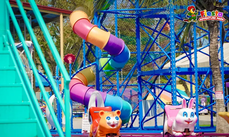 A blue climbing tower with a purple and orange spiral tube slide