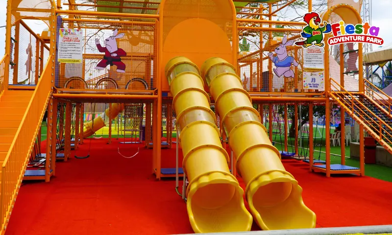 Twin yellow tube slides coming down from an indoor play structure onto a red floor